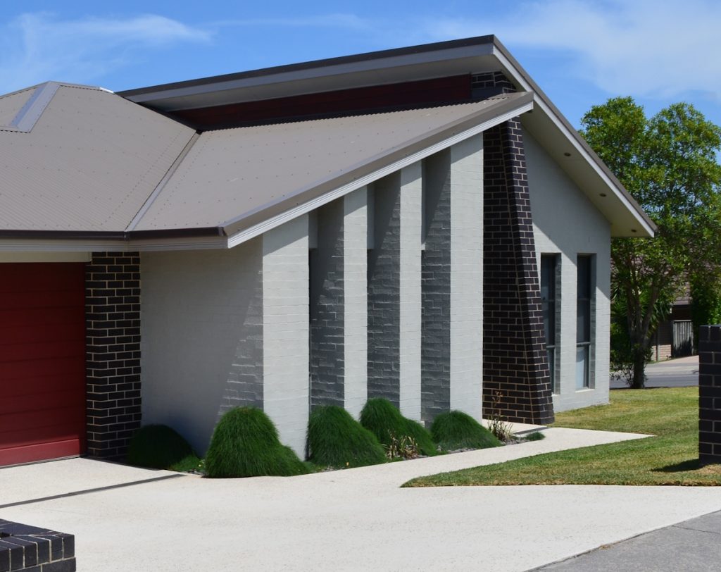 Clean concrete driveway and exterior brick walls of a residential home after pressure cleaning