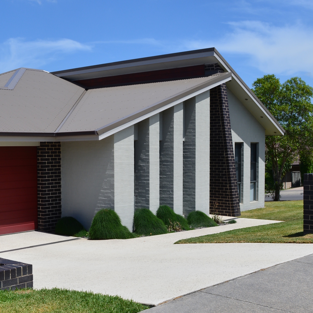 Clean concrete driveway and exterior brick walls of a residential home after pressure cleaning
